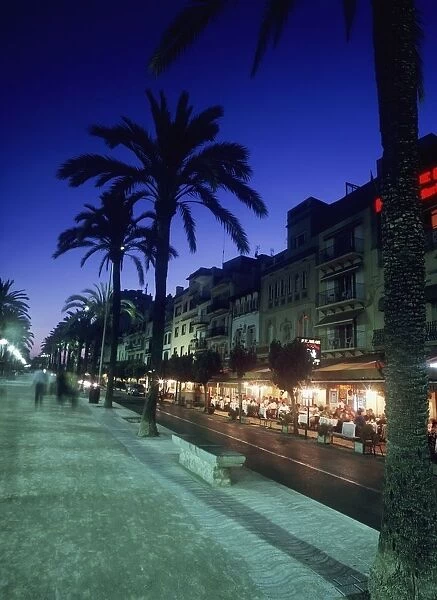 Palm Tree Lined Promenade With People Eating In Restaurants At Dusk