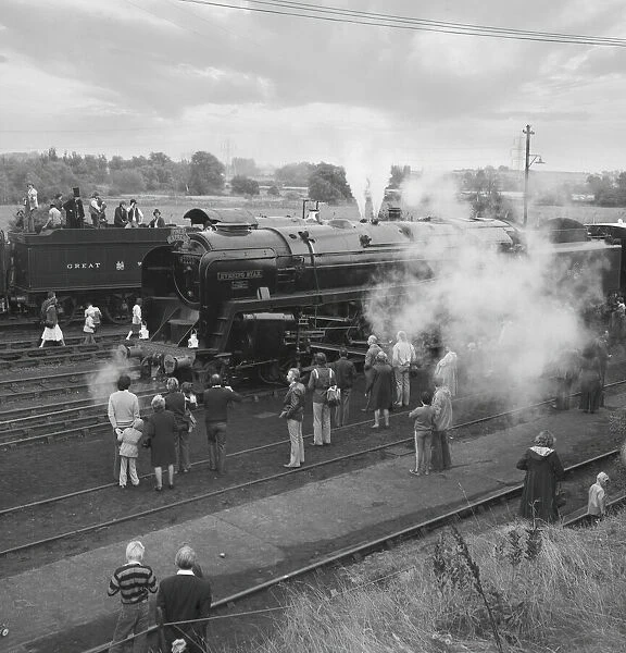 People standing and viewing the steam engine Evening Star on an open day; England