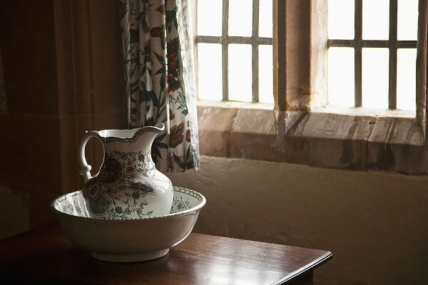 A Pitcher And Basin Sit On The Table Beside A Window; Lindisfarne, Northumberland, England
