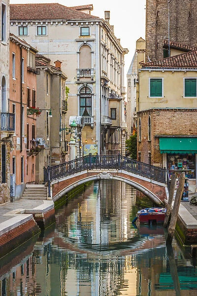 Stone footbridge with iron railing crossing a canal in Venice, Italy