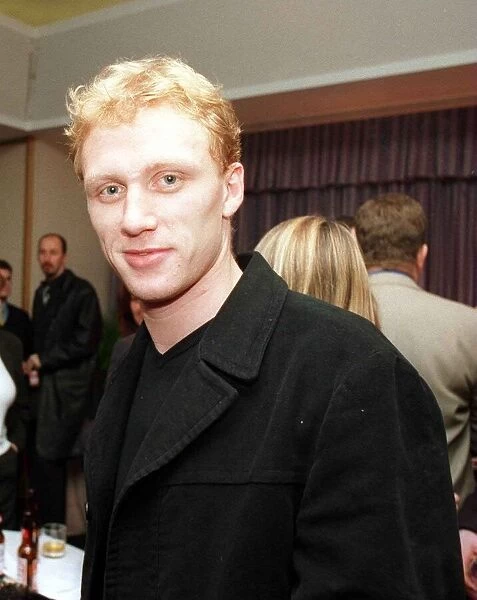 Actor Kevin McKidd wearing black jacket, in a room full of people