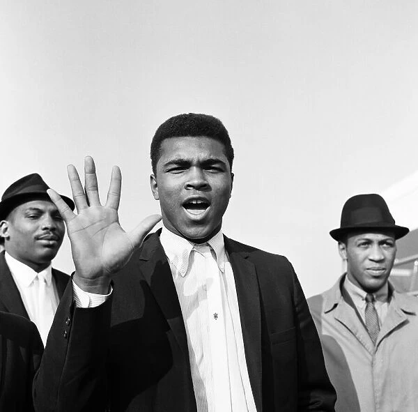Cassius Clay aka (Muhammad Ali) on arrival at London Airport He holds up five