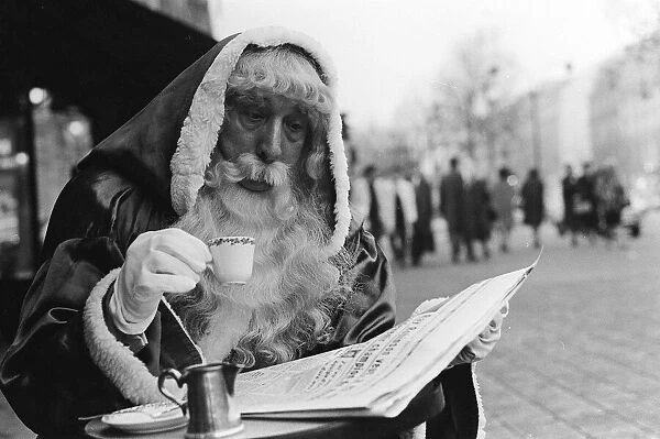 Father Christmas sitting outside a cafe in Paris, reading the newspaper