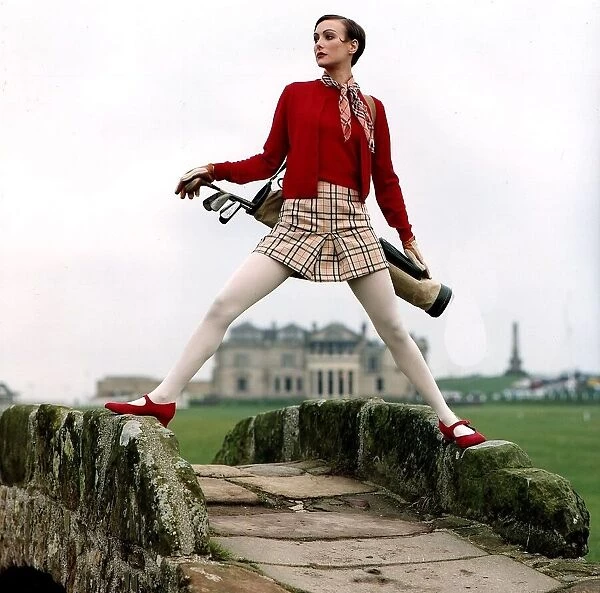 Golf Fashion woman standing astride stone humpback bridge Red shoes twin set jumper