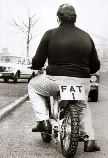 Large man on a small motor cycle with FAT 1 as the licence