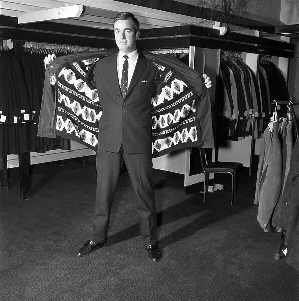 Male model wearing raincoat in menswear department. 1966