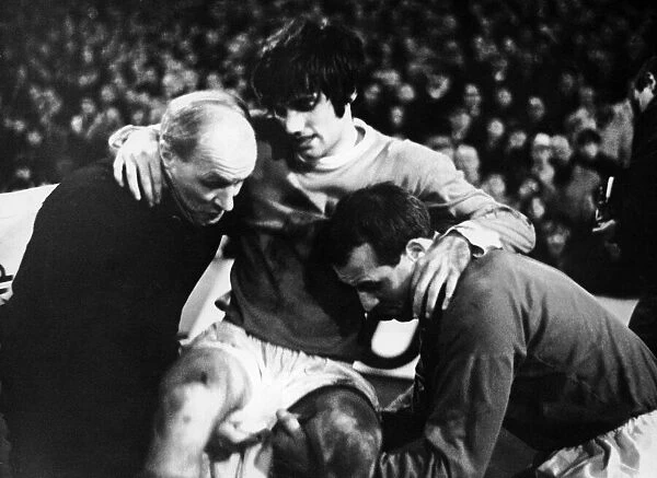 Manchester United footballer George Best is helped off the pitch by trainer Jack