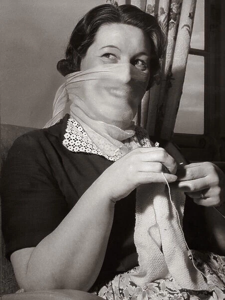 Mrs F Sharpen wearing a veil as she knits at home 1956