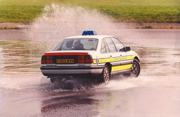 A police patrol car does a skid through a puddle