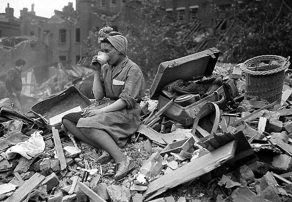 A woman enjoys a cup of tea in the midst of the bomb damage at New Cross after air raids