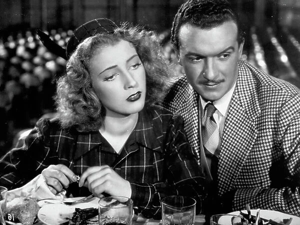 Half-length portrait of a young couple of actors in the film Soltanto un bacio, filmed in 1942. They are seated at a laid table