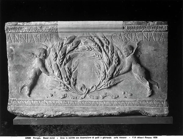 Relief of a roman funerary urn representing two cupids holding a garland in the National Archeological Museum of Umbria, Perugia