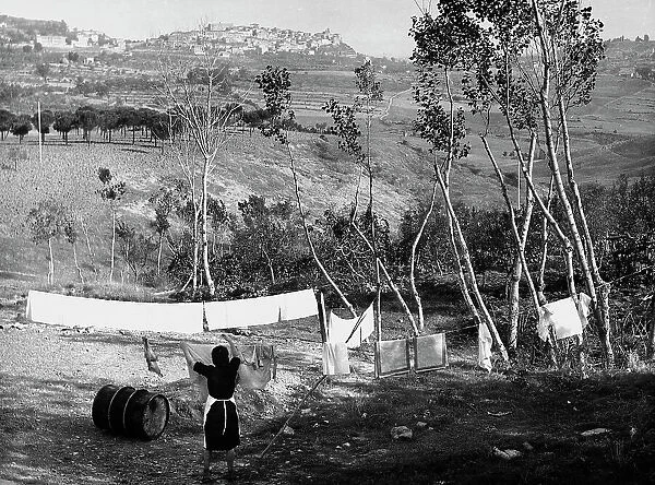 Woman hangs clothes out to dry in the Chianciano countryside