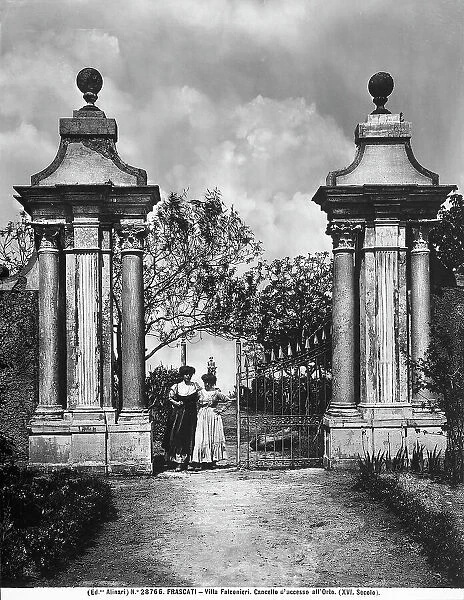 Two women standing near the entrance gate to the orchard of Villa Falconieri in Frascati, province of Rome
