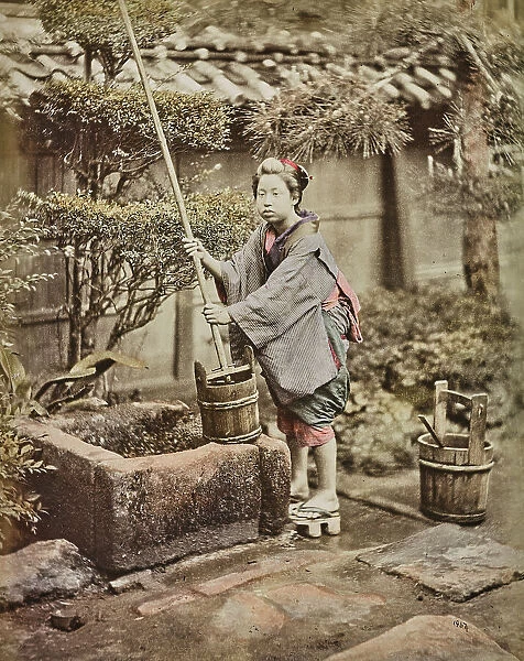 A young Japanese woman collects water from a well