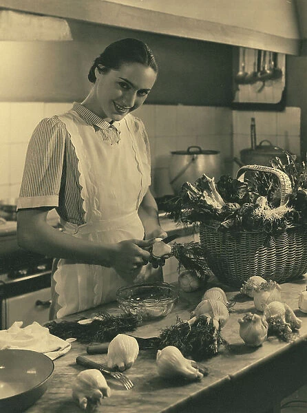 Young woman with apron in the kitchen in front of a table with vegetables