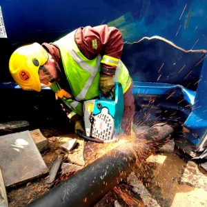 Firefighter cutting through pipe after road traffic accident