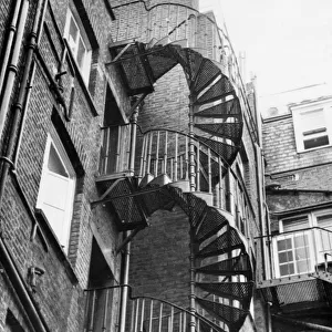 An iron spiral staircase, probably used as a fire escape. Date: 1950s