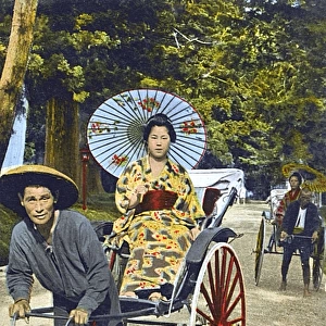 Japanese Woman with paper umbrella transported by Rickshaw