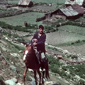 Kashmir - young horseman rides up steep hill