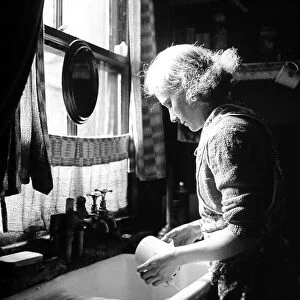 Woman at kitchen sink washing dishes, 1920s 0r 1930s