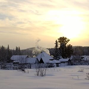 Russian village at midwinter sunset, a typical scene in North Ural Mountains; outskirts of the Vsevolodo-Blagodatskoye village, surrounded by coniferous forest; Russia, december. Ur39. 4477