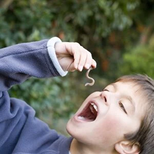 Boy pretending to eat an earthworm