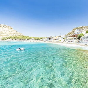 Beach of the seaside town resort of Matala washed by turquoise sea, Crete, Greek Islands