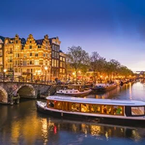 Canal scene with tour boat at dusk, Amsterdam, Netherlands, Europe