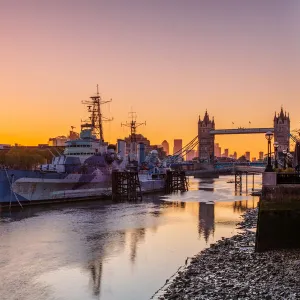 HMS Belfast and Tower Bridge at sunrise with a low tide on the River Thames, London