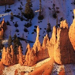 Hoodoos and snow lit by strong dawn light in winter, Queens Garden Trail at Sunrise Point, Bryce Canyon National Park, Utah, United States of America, North America