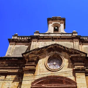 Malta Oratory of The Holy Cross exterior with limestone, Maltese cross and bell tower under a bright blue sky, old city of Birgu (Citta Vittoriosa), Malta, Mediterranean, Europe