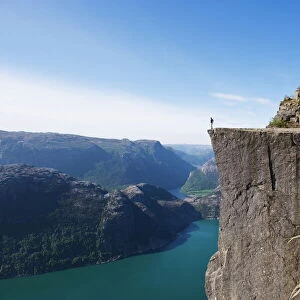 Man standing on Preikestolen (Pulpit Rock) above fjord, Lysefjord, Norway