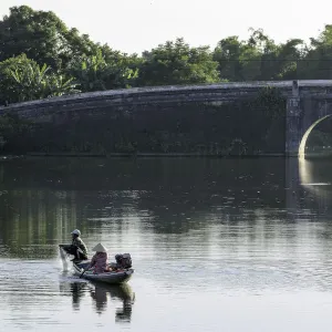 A man and woman fishing from a small boat in the moat around the Citadel in Hue, Vietnam