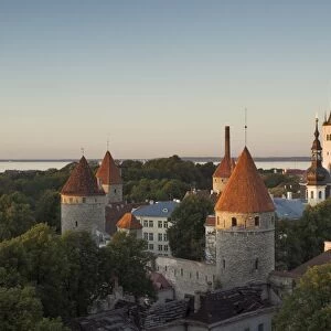 Medieval town walls and spire of St. Olavs church at dusk, Tallinn, Estonia