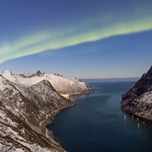 Northern Lights (aurora borealis) on the snowy peaks and the village of Fjordgard
