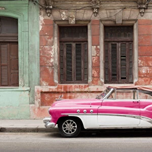 A pink and white vintage American convertible car parked on a street in Havana, Cuba