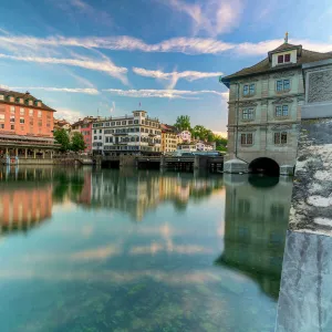 St. Peter church and old buildings of Lindenhof mirrored in Limmat River at dawn, Zurich