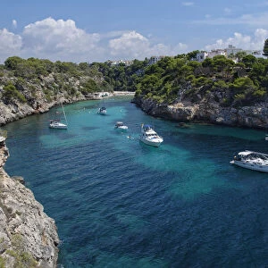 Yachts moored in the cove at Cala Pi, viewed from narrow cliff top coast path