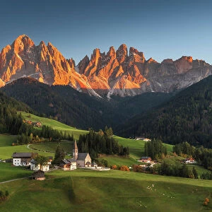 The classic view of the Santa Magdalena church during an early autumn sunset, with the Odle rising tall in the background. Dolomites, Italy