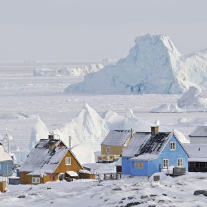 Colourful row of houses with icebergs in the background, Qeqertarsuaq, Disko Island