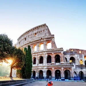 Italy, Rome, a red Vespa motorbike in front of Colosseum at sunrise