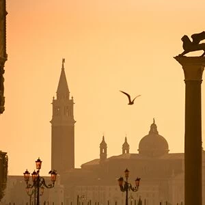 Italy, Veneto, Venice; The Palazzo dei Dogi, the bacino di San Marco with a sculpture of the lion of Venice and San Giorgio Maggiore in