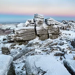 Snow and ice covered moorland at dawn on Belstone Tor in Dartmoor National Park, Devon, England. Winter (December) 2022