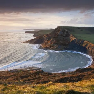 Storm light illuminates Chapmans Pool and Houns Tout cliff, viewed from St Aldhelms Head