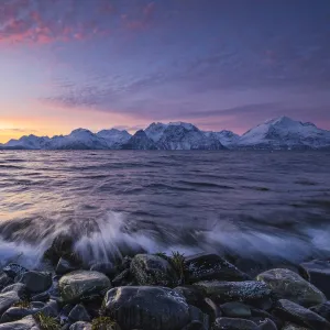 The waves breaking on the stones beach during sunset. Nordmannvik, Kafjord, Lyngen Alps