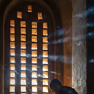 A young monk studying by a window inside a temple, UNESCO, Bagan, Mandalay Region