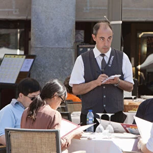 Spain, Madrid, Waiter taking orders from diners at a restaurant in the Plaza Mayor