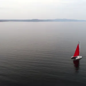 Aerial view shows a couple traveling on a sailing catamaran along the Yenisei River