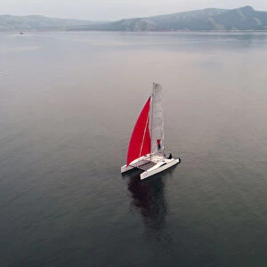 Aerial view shows a couple traveling on a sailing catamaran along the Yenisei River